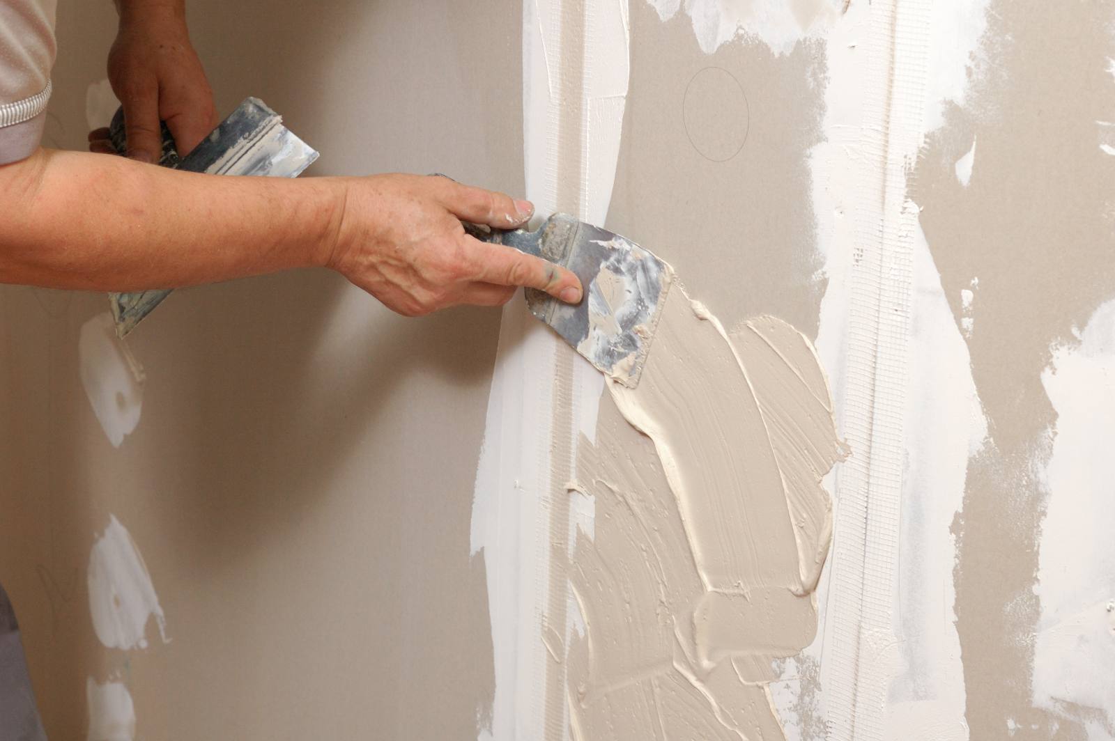 Worker applying joint compound to drywall seam with putty knife
